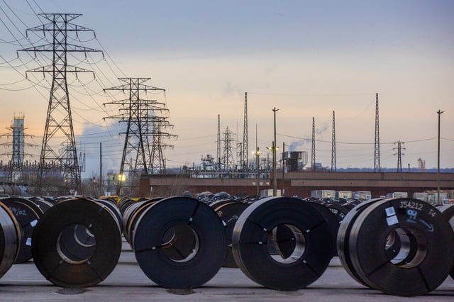 Coils of rolled steel sit in an industrial yard with transmission towers and smokestacks in the background at dusk in Hamilton, Ontario, Canada, January 27, 2025. REUTERS/Carlos Osorio/File Photo