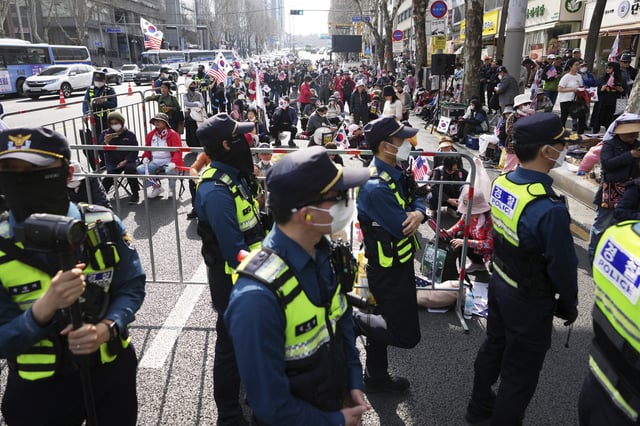 Police officers stand guard as demonstrators stage a rally demanding the arrest of South Korea's main opposition Democratic Party leader Lee Jae-myung near the Seoul High Court in Seoul, South Korea, Wednesday, March 26, 2025. (AP Photo/Lee Jin-man)
