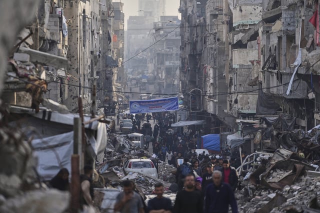 Palestinians walk amid the destruction caused by the Israeli air and ground offensive at Al-Shati camp, Gaza City, Tuesday, March 25, 2025. (AP Photo/Jehad Alshrafi)