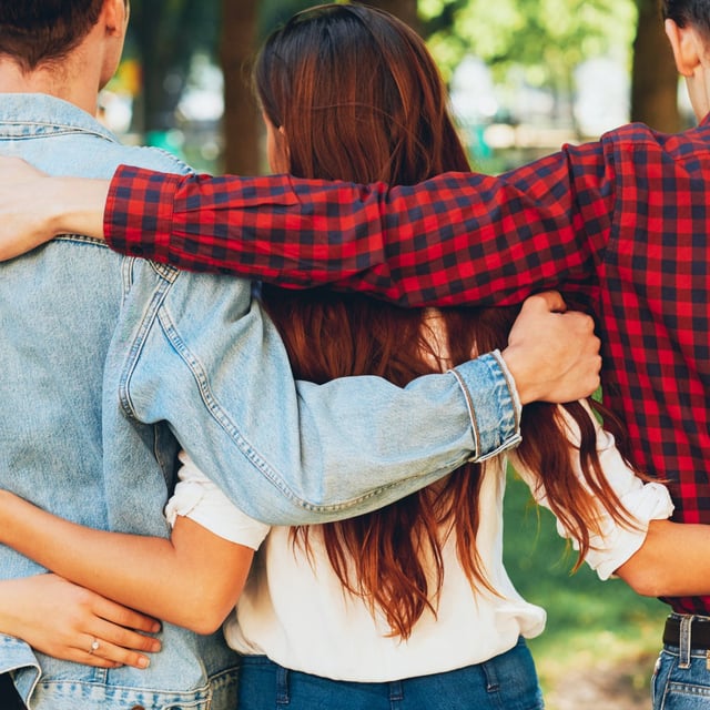backs of two men and two women embracing in a park