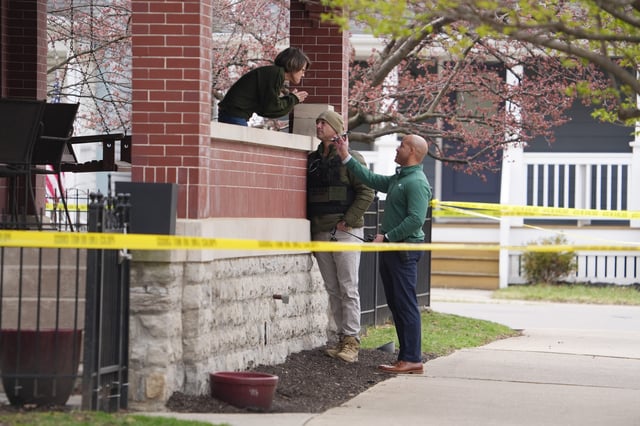 Investigators talk with a resident in the Columbus neighborhood of Victorian Village at the scene where Darnell Jones was shot by a police officer. Jones, who is expected to survive his wounds, is wanted in Toledo for the murder of his daughter, Keimani Latigue.