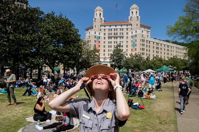 A park ranger with the National Park Service looks up at the solar eclipse while wearing protective eyewear on the Arlington Lawn at Hot Springs National Park in Hot Springs, Arkansas on Monday, April 8, 2024.
