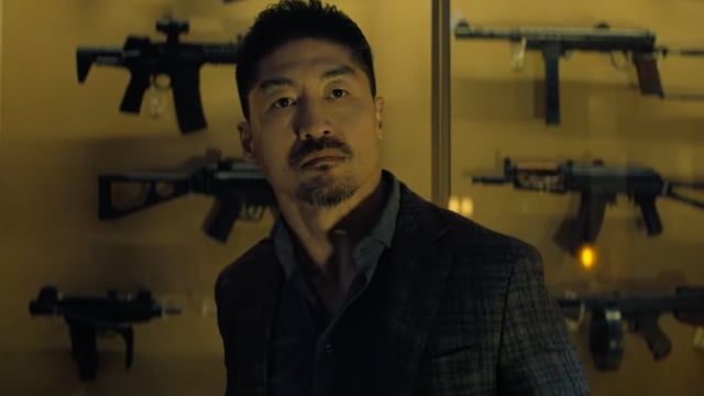 Quinn in front of a case of guns in Reacher Season 3.