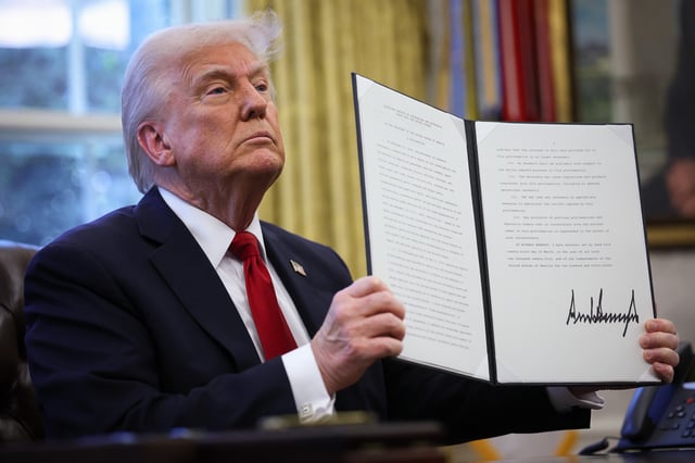 U.S. President Donald Trump displays a signed an executive order in the Oval Office of the White House on March 26, 2025 in Washington, DC.