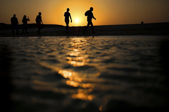 FILE - Tourists walk on the Giftun Island beach as the sun sets over the Red Sea in Hurghada, Egypt, Thursday Aug. 20, 2015. (AP Photo/Hassan Ammar, File)