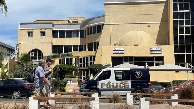 People walk next to an Egyptian police vehicle in front of the hospital where the bodies of foreigners who were killed when a tourist submarine sank off Egypt's Red Sea resort city of Hurghada are kept in Hurghada, Egypt, March 27, 2025.