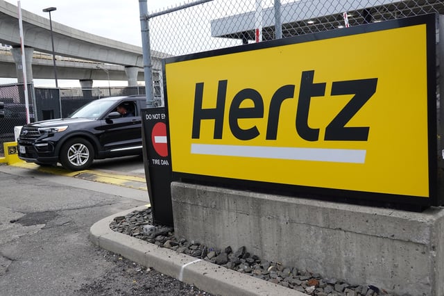 A car exits a lot and passes by Hertz rental car signage at John F. Kennedy International Airport in Queens, New York City, U.S., March 30, 2022. REUTERS/Andrew Kelly/File Photo