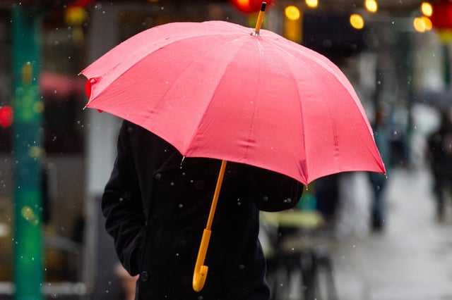 A pedestrian crosses a street holding an umbrella during a rainstorm in Alameda, Calif., on March 12, 2025.