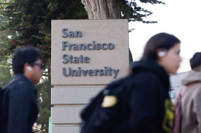Students walk past a San Francisco State University sign on campus in September.