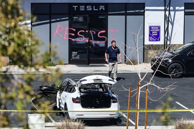 An investigator looks over the scene at a Tesla Collision Center after several vehicles were set on fire on March 18, 2025 in Las Vegas.