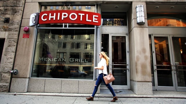 Woman walking in front of a Chipotle location.