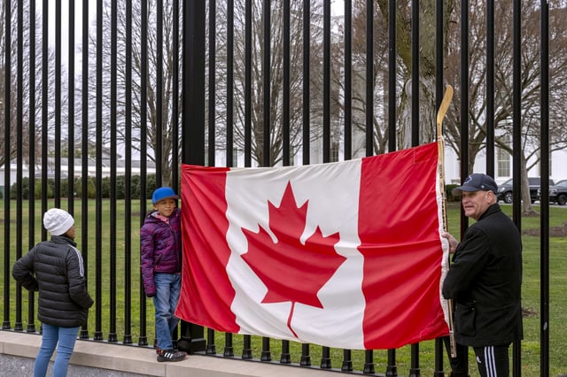 FILE - Toronto residents Douglas Bloomfield, from right, his son Phoenix and wife Ame, who are on vacation in Washington, hold a Canadian flag and an ice hockey stick to show their support for Canada regarding trade tariffs in front of the White House in Washington, March 13, 2025. (AP Photo/Ben Curtis, File)