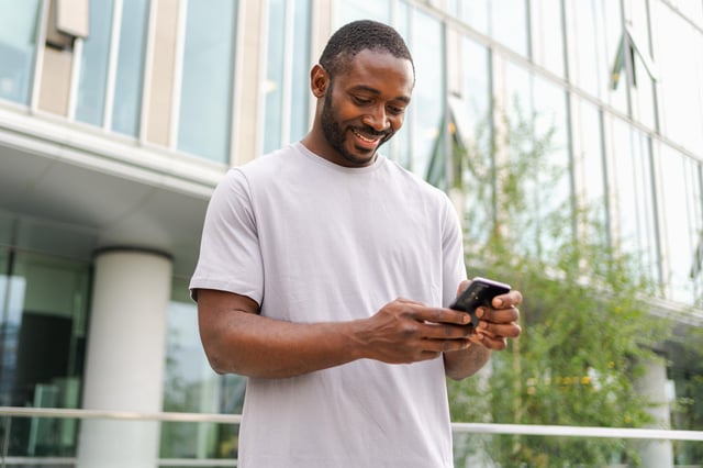 In this stock image, a man uses his mobile phone while on a city street.