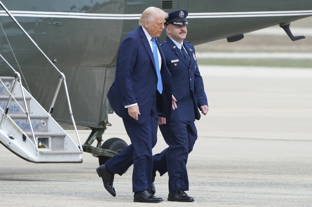 President Donald Trump, left, walks with Col. Paul Pawluk, Vice Commander of the 89th Airlift Wing, from Marine One to board Air Force One at Joint Base Andrews, Md., Friday, March 28, 2025, en route to Florida for the weekend. (AP Photo/Jacquelyn Martin)