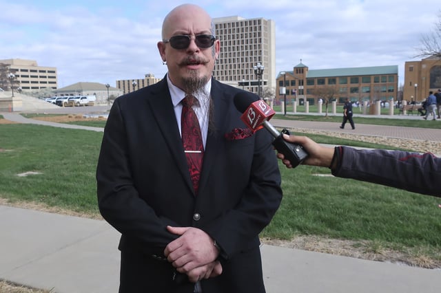 Michael Stewart, the President of the Kansas City-area Satanic Grotto, speaks with reporters as the group's rally gets started outside the Kansas Statehouse, Friday, March 28, 2025, in Topeka, Kansas. (AP Photo/John Hanna)