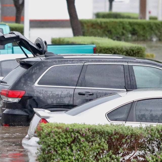 A man closes the trunk of his vehicle after it was caught in a flood in near the McAllen Convention Center during a downpour on Thursday, March 27, 2025, in McAllen., Texas.  (Joel Martinez /The Monitor via AP)