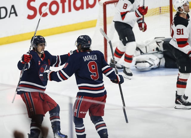 Winnipeg Jets' Alex Iafallo (9) and Mark Scheifele (55) celebrates Iafallo's goal against the New Jersey Devils during first period NHL action in Winnipeg on Friday, March 28, 2025. THE CANADIAN PRESS/John Woods