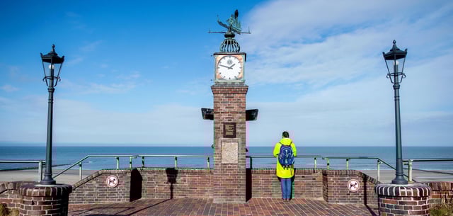 Wangerooge: Eine Frau steht an der historischen Uhr der Strandpromenade