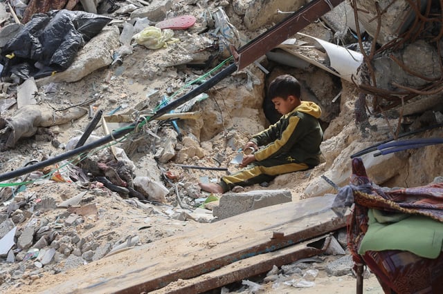 A Palestinian boy plays amidst the debris of a building destroyed during the Israel-Hamas war, in Gaza City on March 28, 2025. Palestinian sources close to Hamas told AFP that talks were underway between the militant group and mediators from Egypt and Qatar on March 27, to revive a ceasefire and hostage release deal for Gaza. (Photo by Omar AL-QATTAA / AFP) (Photo by OMAR AL-QATTAA/AFP via Getty Images)          
