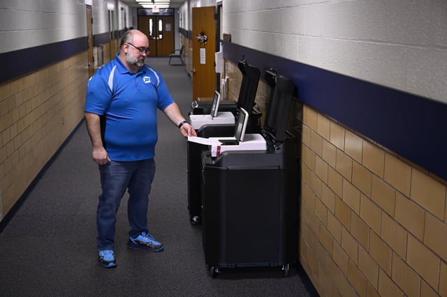 Christopher Prue, president of the Registrars of Voters Association of Connecticut, demonstrates how a ballot is inserted into one of the new voting tabulators at the Registrars of Voters Office, Thursday, March 27, 2025, in Vernon, Conn. (AP Photo/Jessica Hill)