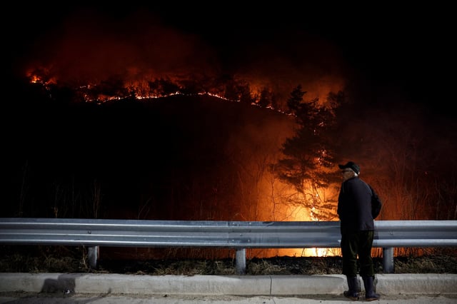 A man stands as a wildfire devastates the area in Andong, South Korea, March 26, 2025. REUTERS/Kim Hong-Ji/File Photo
