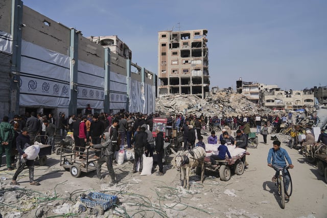 Palestinians receive bags of flour and other humanitarian aid distributed by UNRWA, the U.N. agency helping Palestinian refugees in Jabaliya, Gaza Strip on Tuesday, March 25, 2025. (AP Photo/Jehad Alshrafi)