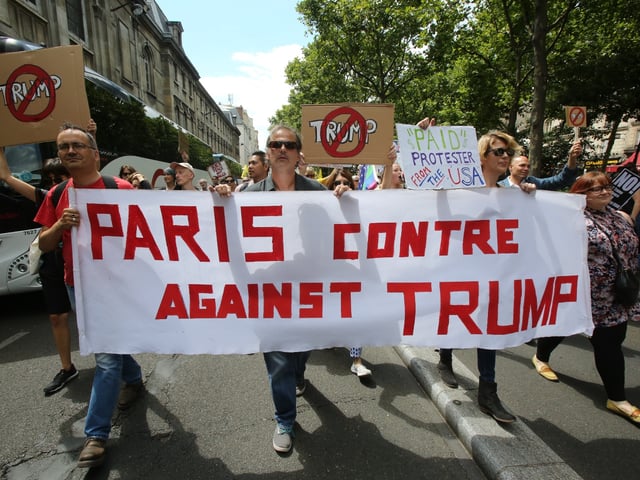 PARIS, FRANCE - JULY 14: Americans in Paris, in a group called "Paris against Trump," join French anti-Macron groups, for a protest march, coinciding with Trump's visit to Paris, on July 14, 2017 in Paris, France. (Photo by Owen Franken - Corbis/Corbis via Getty Images)