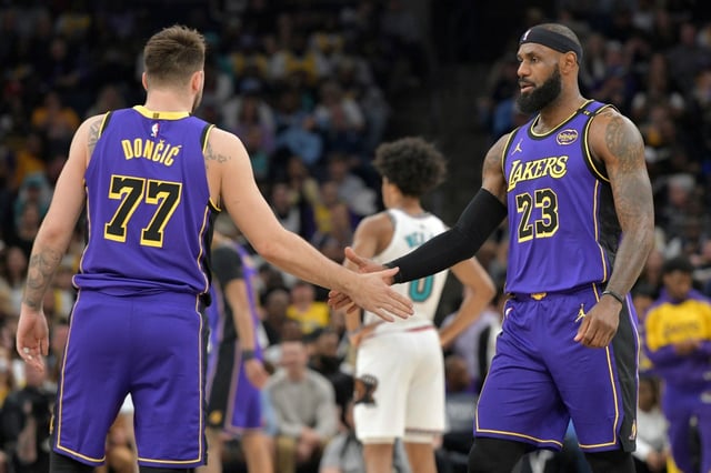 Lakers guard Luka Doncic (77) and forward LeBron James (23) greet each other on the court in the first half of an NBA basketball game against the Memphis Grizzlies, Saturday, March 29, 2025, in Memphis, Tenn. (AP Photo/Brandon Dill)