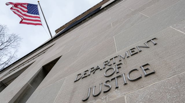 The U.S. Flag flies above a sign marking the Justice Department headquarters building in Washington, D.C. Photo: J. David Ake/Getty Images