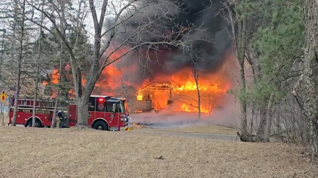 Firefighters work near a building engulfed in fire following a plane crash in Brooklyn Park, Minnesota on March 30, 2025.