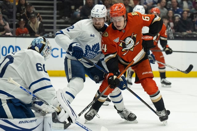 Ducks right wing Sam Colangelo (64) deflects a shot as Toronto Maple Leafs defenseman Simon Benoit (2) defends during the first period of an NHL hockey game, Sunday, March 30, 2025, in Anaheim, Calif. (AP Photo/Kyusung Gong)