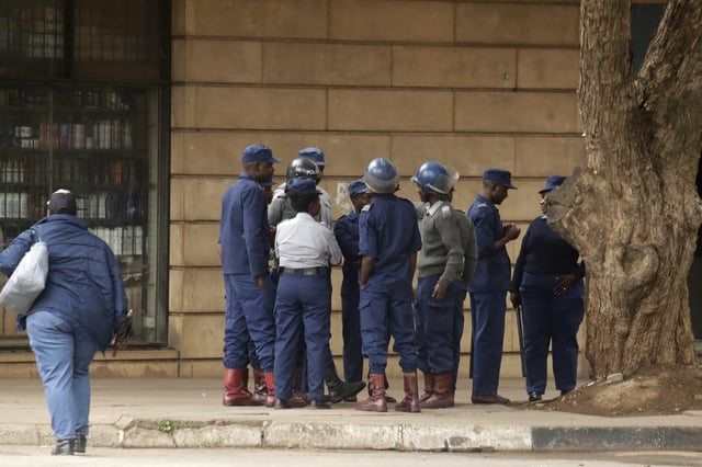 Riot police officers gather on a deserted street in downtown Harare, Zimbabwe, Monday, March 31, 2025, following calls for an anti-government protest. (AP Photo/Aaron Ufumeli)