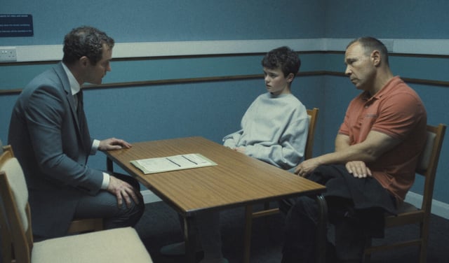 Ein Junge und zwei Männer sitzen an einem Verhörtisch – eine Szene aus der Netflix-Serie „Adolescence“