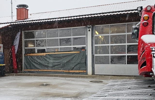Ein beschädigtes Rolltor an einer Garage für Pistenraupen ist mit einer Plane abgedeckt