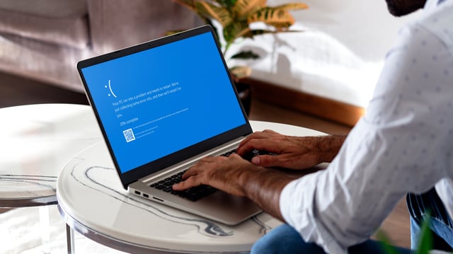 Man with laptop showing Blue screen of death or BSOD on the monitor screen