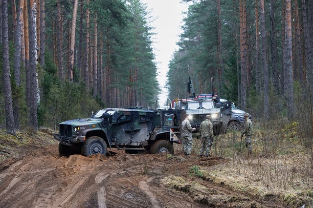 U.S. soldiers stand near military vehicles parked at a training range in Pabrade, north of the capital Vilnius, Lithuania on Thursday, March 27, 2025. (AP Photo/Mindaugas Kulbis)