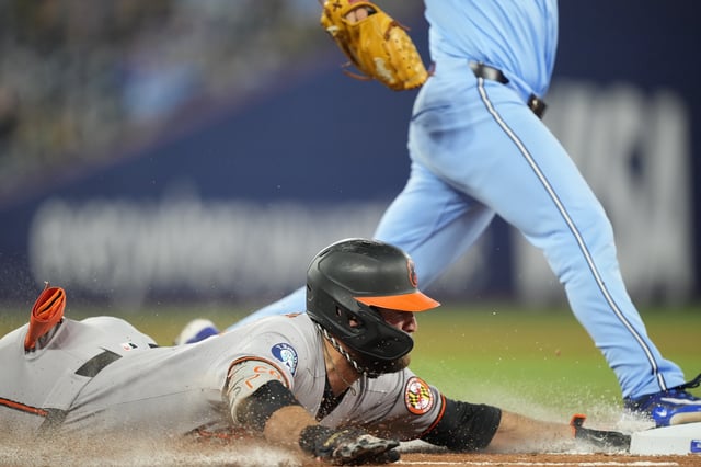 Mar 30, 2025; Toronto, Ontario, CAN; Baltimore Orioles left fielder Colton Cowser (17) dives to first base against the Toronto Blue Jays during the seventh inning at Rogers Centre. Mandatory Credit: John E. Sokolowski-Imagn Images