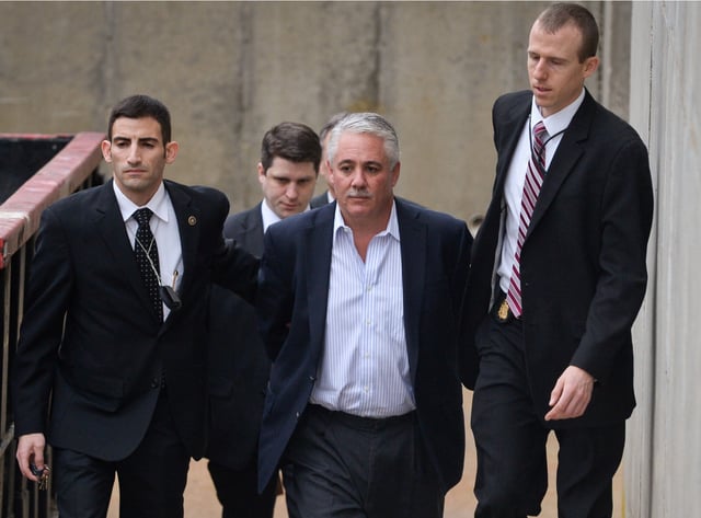 In this Dec. 9, 2015 file photo, former Suffolk County Police Chief James Burke is escorted to a vehicle by FBI personnel outside an FBI office in Melville, N.Y.