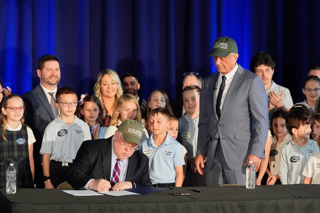 Health and Human Services Secretary Robert F. Kennedy Jr., right, watches as West Virginia Gov. Patrick Morrisey signs a letter of intent to request changes to the state's SNAP and food dye legislation, Friday, March 28, 2025, in Martinsburg, W. Va. (AP Photo/Stephanie Scarbrough)