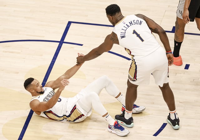 Zion Williamson #1 of the New Orleans Pelicans helps up teammate CJ McCollum #3 during the first half of a game against the San Antonio Spurs at the Smoothie King Center on February 25, 2025 in New Orleans, Louisiana.