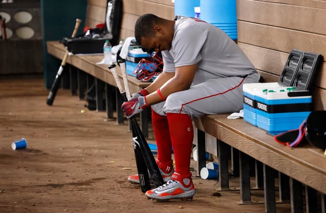 Rafael Devers sits in the Boston Red Sox dugout after striking out against the Texas Rangers during Sunday's game at Globe Life Field in Arlington, Texas.