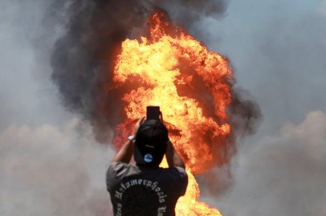 An onlooker takes a picture of a fire after a gas pipeline operated by Malaysia's state energy firm Petronas caught fire, in Puchong, Malaysia April 1, 2025. REUTERS/Stringer