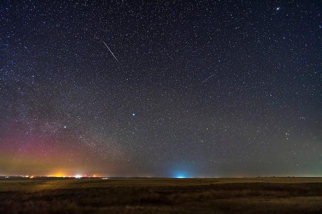 Two Lyrid meteors streak away from the shower’s radiant in this 2023 photo. Also visible is a dim aurora to the northeast. Credit: Alan Dyer