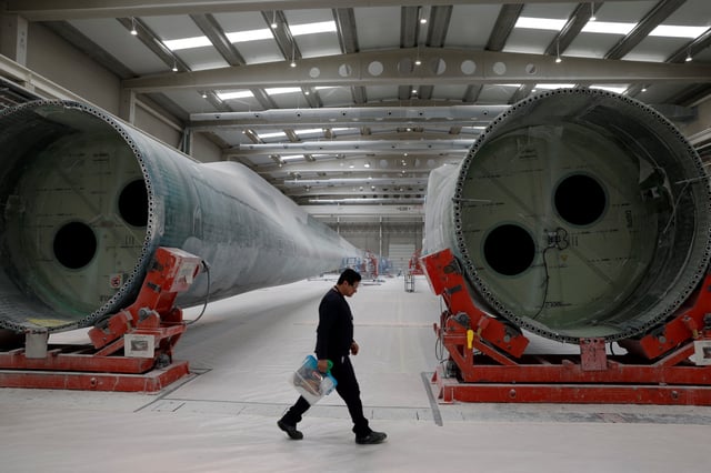 A person walks by as workers build wind turbine blades at the Nordex blades factory in Lumbier, Spain, March 18, 2024. REUTERS/Vincent West/File Photo