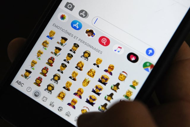 Stock Image: A person holds an iPhone showing emojis in Hong Kong, on October 30, 2019.