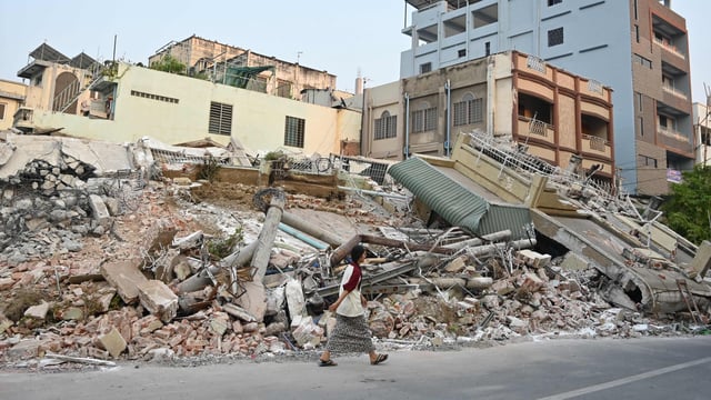 A woman walks past destroyed buildings in Mandalay on April 1, 2025, four days after a major earthquake struck central Myanmar.