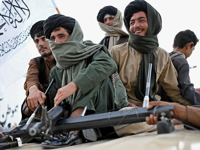 Taliban fighters travel in a vehicle as they celebrate the first anniversary of the withdrawal of US-led troops from Afghanistan, near the airport in Kabul on August 31, 2022. The Taliban declared on August 31 a national holiday and lit up the capital with coloured lights to celebrate the first anniversary of the withdrawal of US-led troops from Afghanistan after a brutal 20-year war. (Photo by Wakil kohsar / AFP)