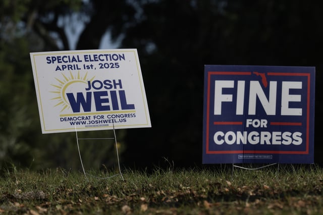 Campaign signs sit on the side of the road supporting Democratic nominee Josh Weil outside of his campaign event at the Silver Springs Shores Community Center on March 26, 2025, in Ocala, Florida.