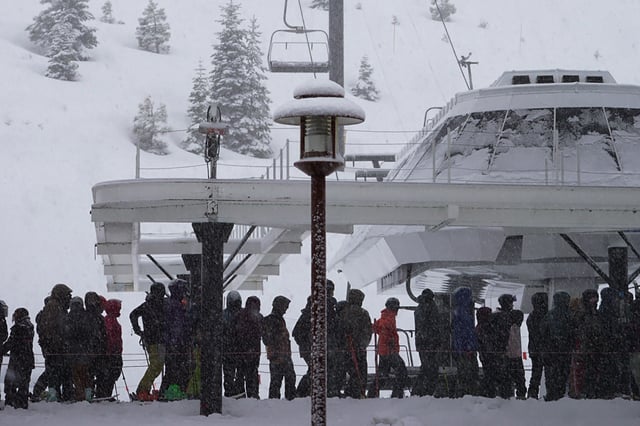 Skiers and snowboarders pack a ski lift at Palisades Tahoe on March 31, 2025, during a snowfall.