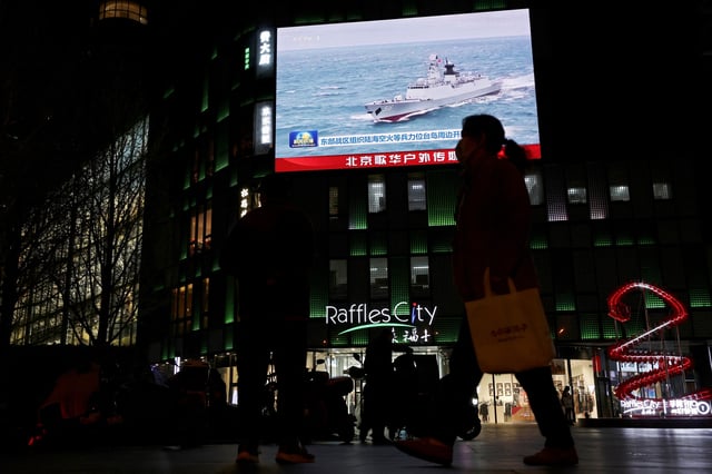 A Chinese navy vessel is seen on a giant screen showing news footage about joint army, navy, air and rocket forces drills around Taiwan by the Chinese People's Liberation Army (PLA), outside a shopping mall in Beijing, China, April 1, 2025. REUTERS/Florence Lo